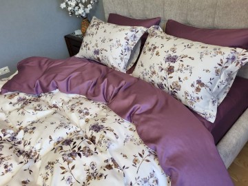 The satin bedding set features a richly colored sheet and pillowcases with a floral print on a white background. Satin bedding made from 100% cotton grown without the use of pesticides.